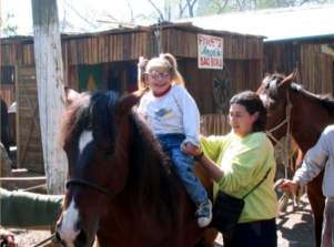 Foto de uma menina andando a cavalo