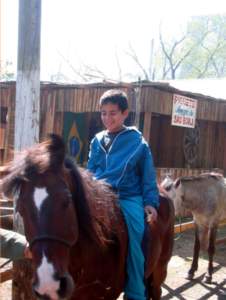 Foto de um menino andando a cavalo